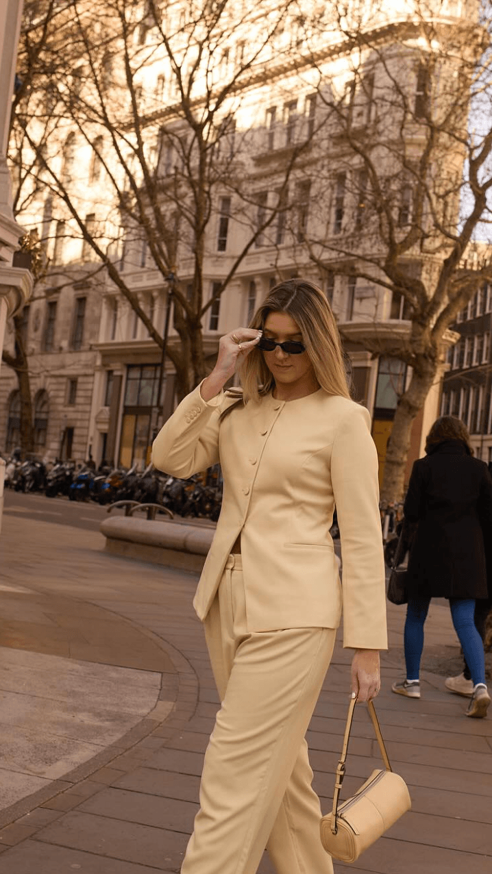 Image may contain Accessories Bag Handbag Clothing Formal Wear Suit Coat Pedestrian Person Adult and Blazer